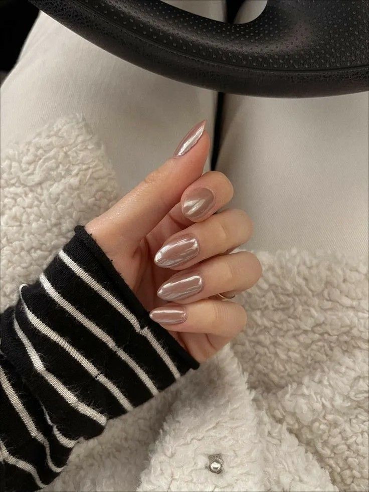 Long, almond nails with a pale, cool-toned taupe-silver metallic finish against a silky, champagne-colored shirt.